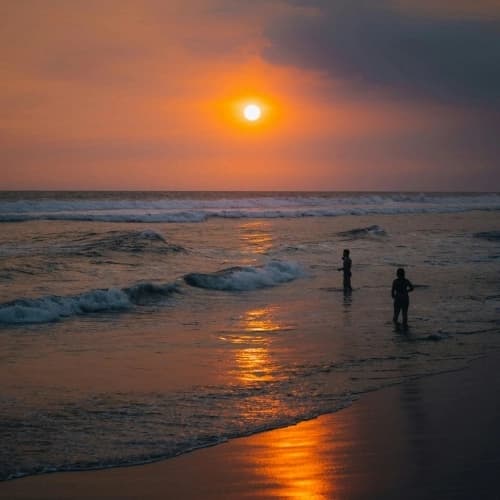 Surfer and waves on the black-sand beach of El Paredón